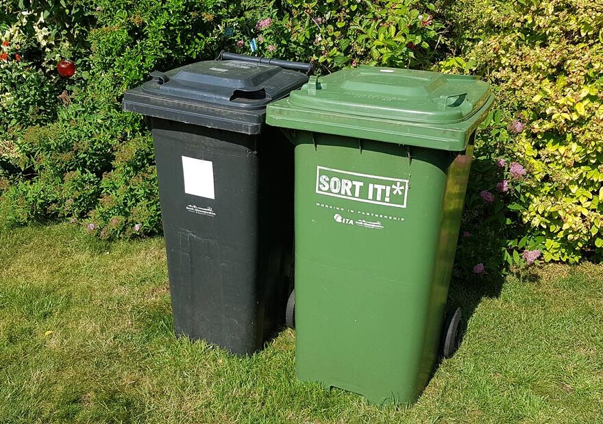 Photo of two plastic domestic waste bins, one black, one green.