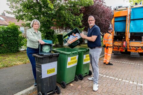 Photo of two councillors emptying recycling containers into bins.