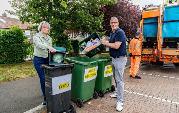 Photo of two councillors emptying recycling containers into bins.